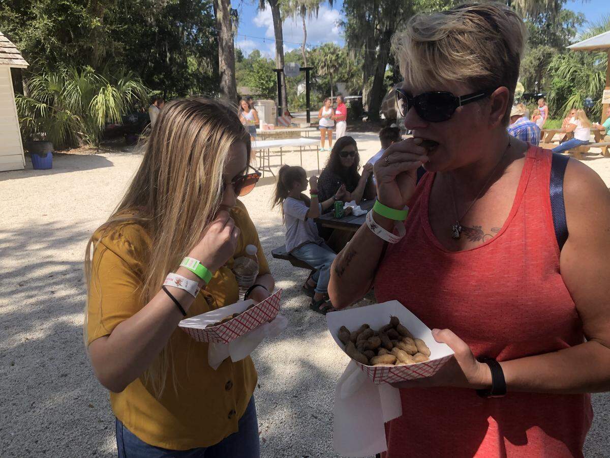 Festival attendees Dawn Fedele and Brittany Yeager crack open their boiled peanuts in Old Town Bluffton. “It’s a southern thing,” Fedele said.