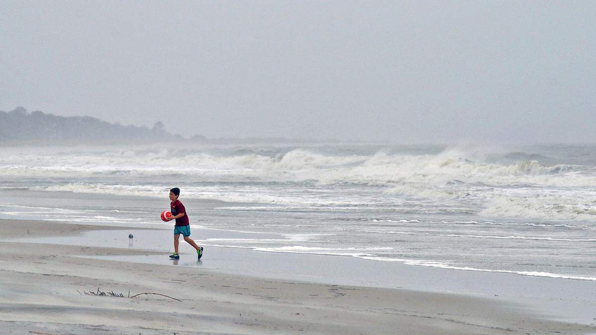 A young boy secures his soccer ball and runs from the water at Burke’s Beach mid-island at Hilton Head Island, SC on Wednesday, September 4, 2019.