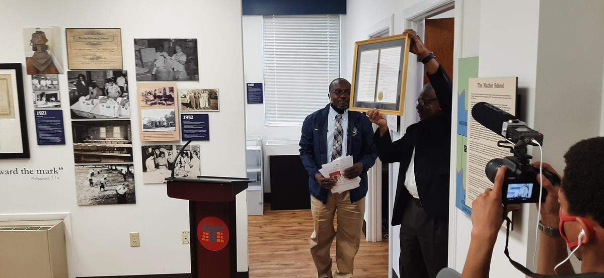 Rufus Pinckney holds up a state Legislature proclamation as state Rep. Michael Rivers looks on.
