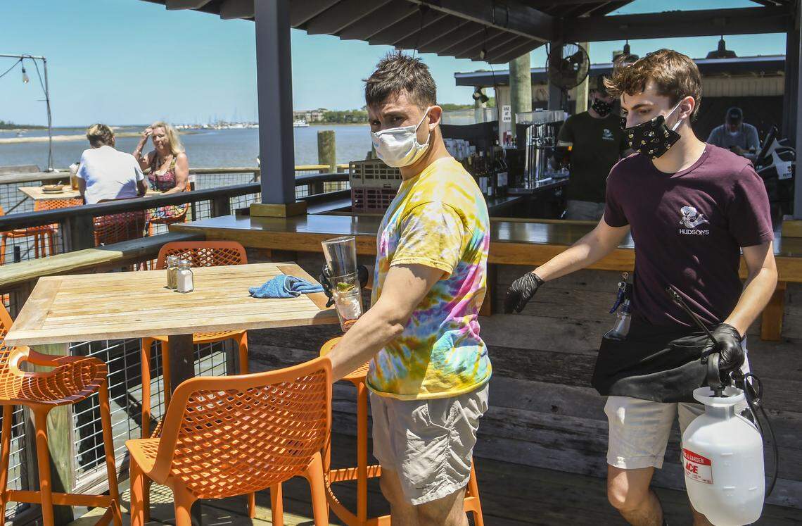 Carlos Corona, left, clears the dishes from the table at Hudson’s Seafood House on the Docks as A.J. Kestler, right, prepares to sanitize the chairs and table with a disenfectant on Monday, May 4, 2020 on Hilton Head Island. Monday marked the first day that restaurants could serve customers in outdoor spaces if certain precautions were met to help stave off the spread of the coronavirus.
