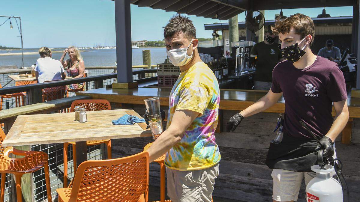 Carlos Corona, left, clears the dishes from the table at Hudson’s Seafood House on the Docks as A.J. Kestler, right, prepares to sanitize the chairs and table with a disenfectant on Monday, May 4, 2020 on Hilton Head Island. Monday marked the first day that restaurants could serve customers in outdoor spaces if certain precautions were met to help stave off the spread of the coronavirus.