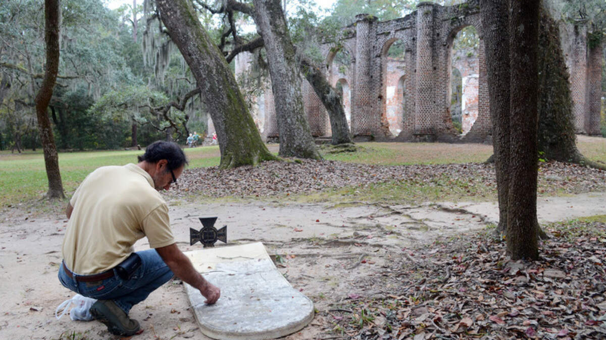 Frank Genello, a conservator out of Charleston, inspects a damaged tombstone on Monday at Old Sheldon Church. The tombstone was one of several knocked over and smashed by vandals over the weekend, causing an estimated $20,000 in damage, according to the caretaker.