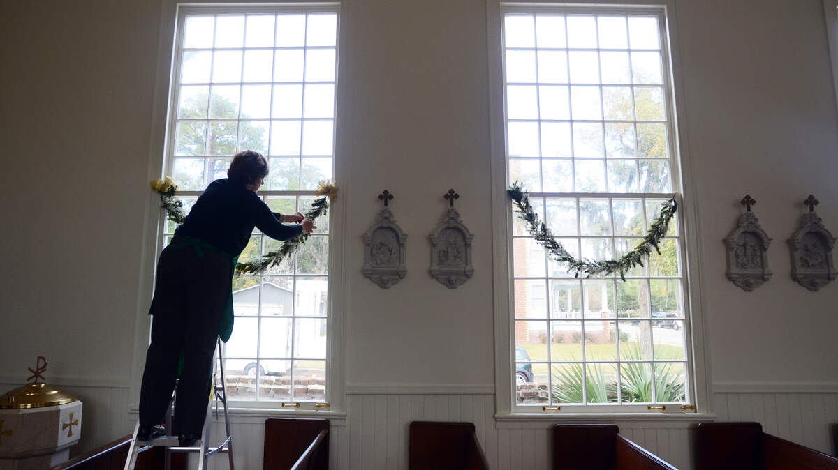 Lee French decorates a window Nov. 21, 2013, as she helps prepare  St. Peter's Historic Catholic Church on Carteret Street for this  weekend's Homes for the Holidays home tour.