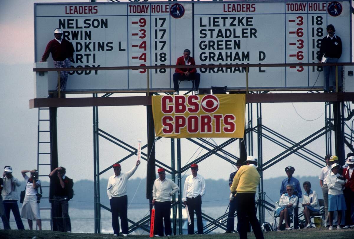 In this undated photo estimated to be from the seventies, volunteers hold up quiet signs as a putt is being made with the leader board in the background.