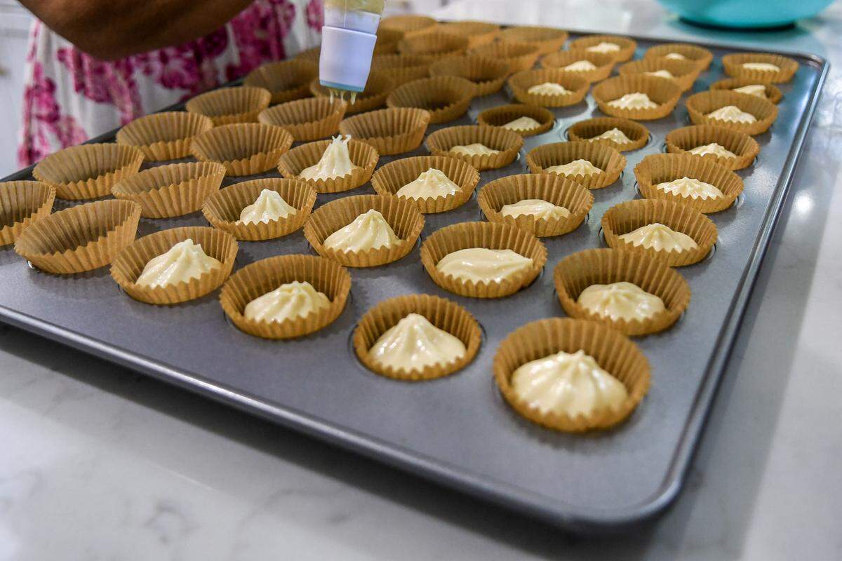 Nicole Lust, owner of Petite Sweets, uses a pastry bag to reduce the mess of filling baking cups on Aug. 26, 2025, at her Hilton Head Island home.