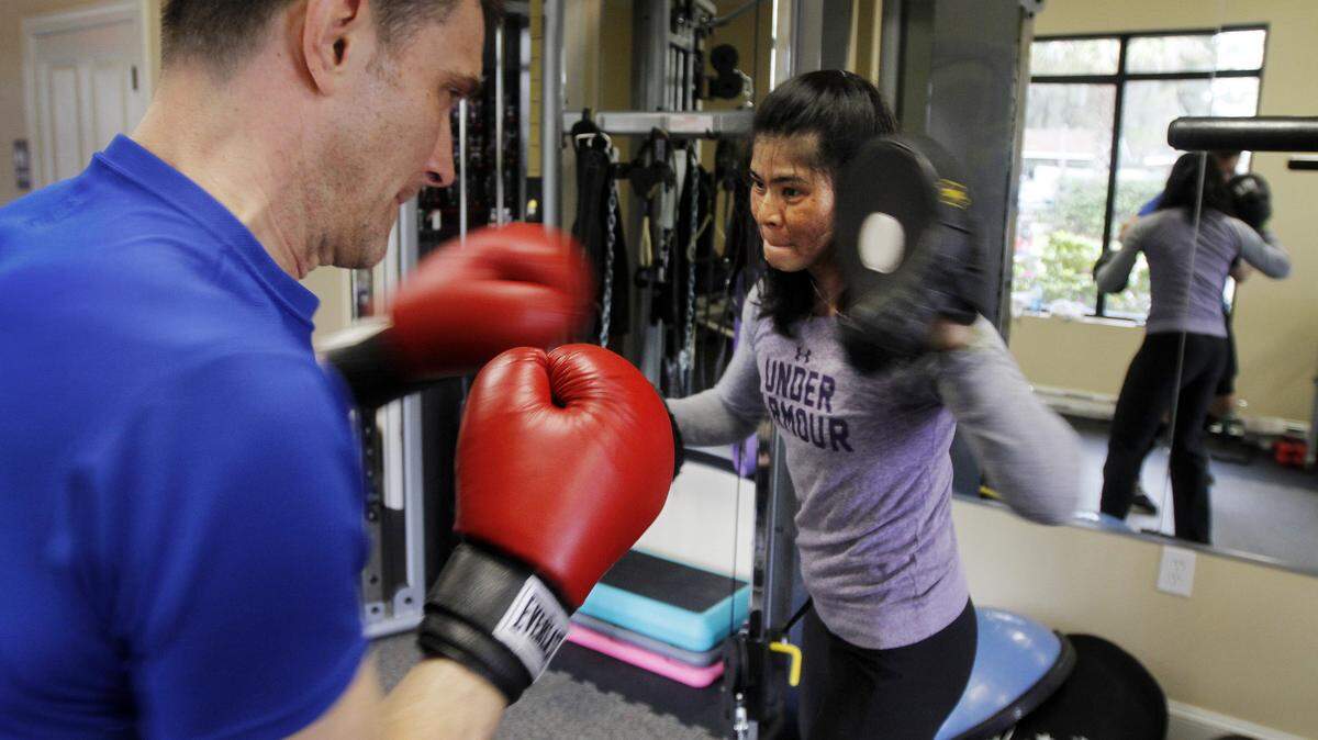 Mina Truong, co-owner of "Mina & Conroy Fitness Studio," spots Benjamin J. Shermeta, of Philedelphia, left, during a workout utilizing boxing gloves on March 23, 2015. Shermeta is the son-in-law of co-owner Pat Conroy, not pictured.