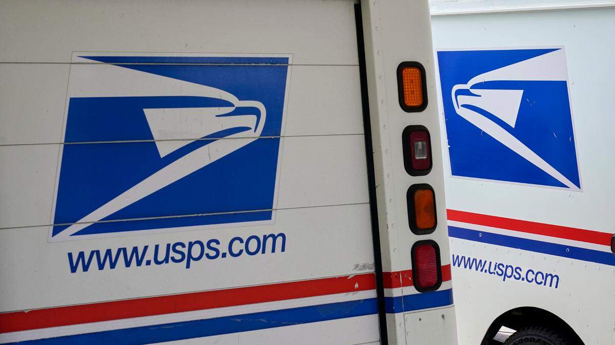 In this Aug. 18, 2020, file photo, mail delivery vehicles are parked outside a post office in Boys Town, Neb.