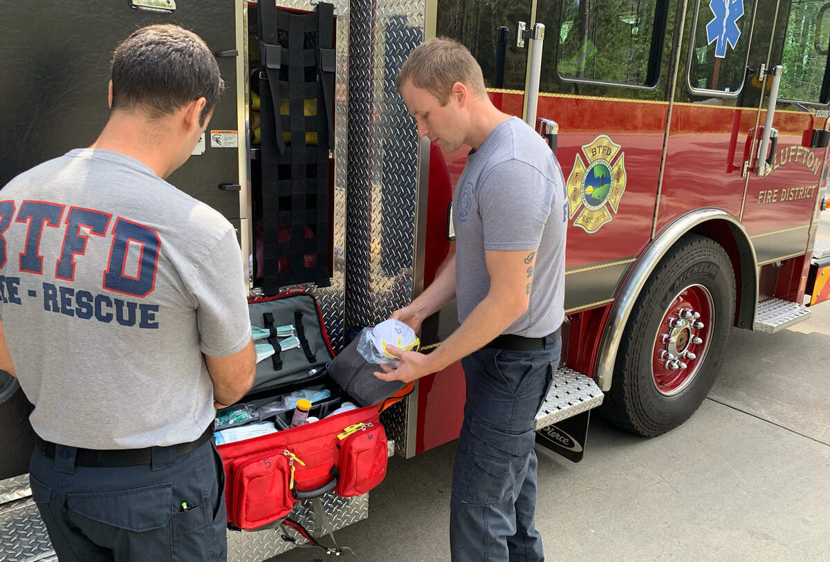 In this hand out photo taken at Bluffton Township Fire District Headquarters Station 35, firefighter Scott Smith, left, and firefighter/paramedic Carson Stone display some of the personal protective equipment the department uses for emergency calls.
