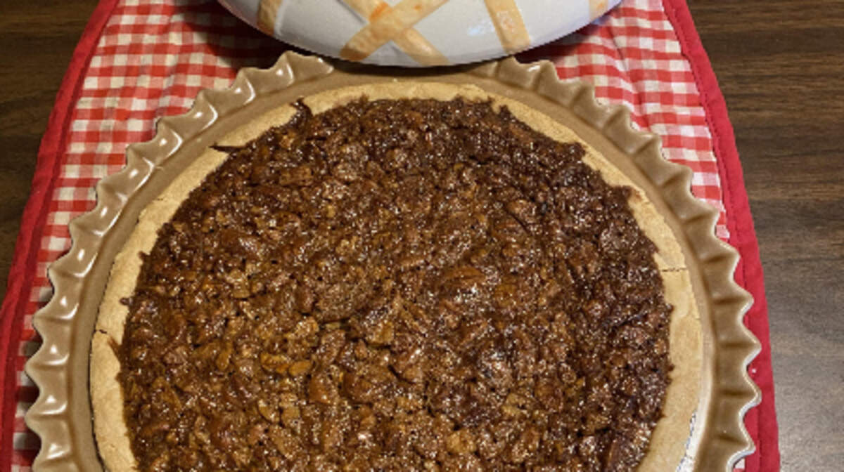 A baked to perfection pecan pie awaits slicing.
