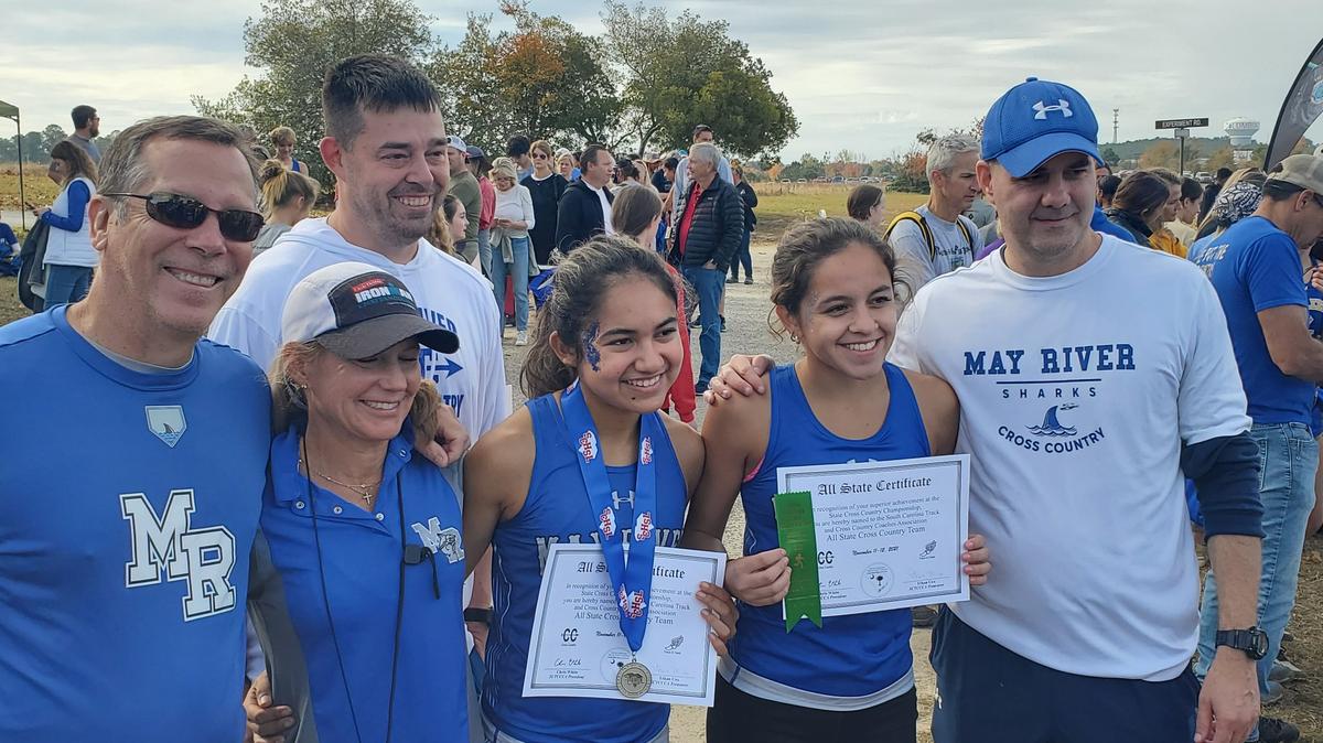 May River runners, Anya Arroyo and Victoria Sosa (middle) pose with with their all-state certificates after Thursday’s Class 4A state cross country meet.