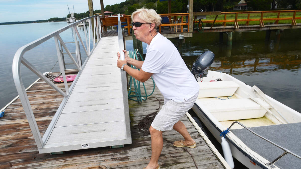 Bluffton's Dyane Lee demonstrates Aug. 22, 2013,  how she had to brace herself in order to keep from falling off her dock when the wake from a speeding boat hit. To prevent such incidents in the future, Lee would like to see her area of the May River made into a no-wake zone. The zone would run between the Bluffton Oyster Co. on Wharf Street and public dock on Calhoun Street.