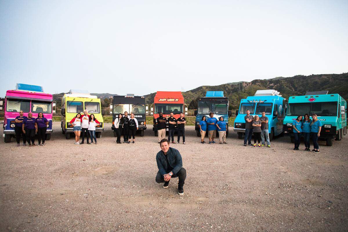 Buns ‘n’ Thighs , Chop Shop, Heroes On A Half Shell, Just Wing It, Mobile Moo Shu, New England Grill, and Sassy Soul team members in front of their trucks with host Tyler Florence, as seen on The Great Food Truck Race, Season 9.