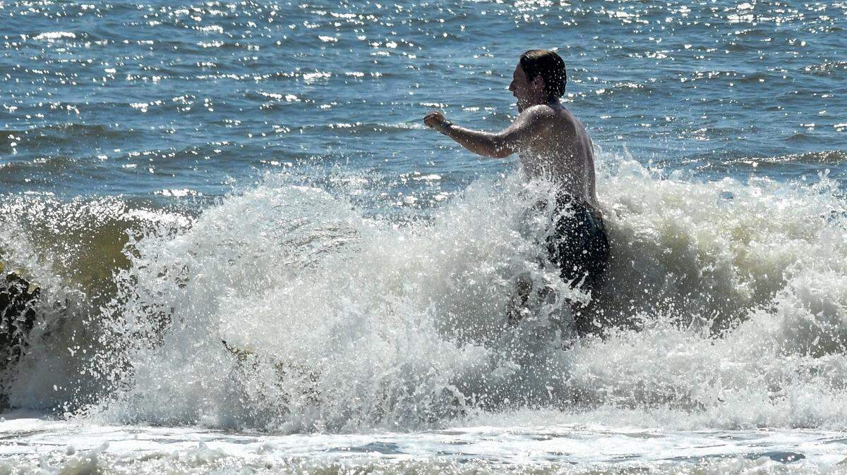 Will Batson, vacationing from New Jersey, attempts to surf on Tuesday, Aug. 19, 2025, at Burkes Beach on Hilton Head Island. Low tide made surfing difficult as Hurricane Erin churns in the Atlantic Ocean, forecasted to steer away from the eastern seaboard. Batson, on his first week of vacation, said he planned to return for high tide when the waves should be bigger.