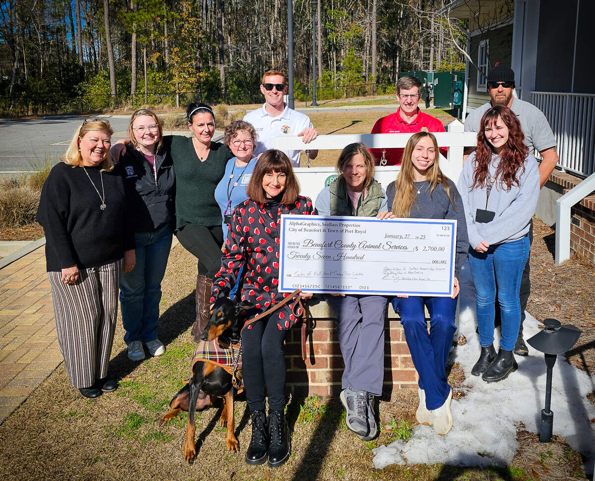 Rebecca W. Bass and her certified therapy dog Ocho deliver a check to Beaufort County Animal Services. The money was raised from sales of a calendar featuring certified therapy dogs and firefighters with the Beaufort-Port Royal Fire Department.