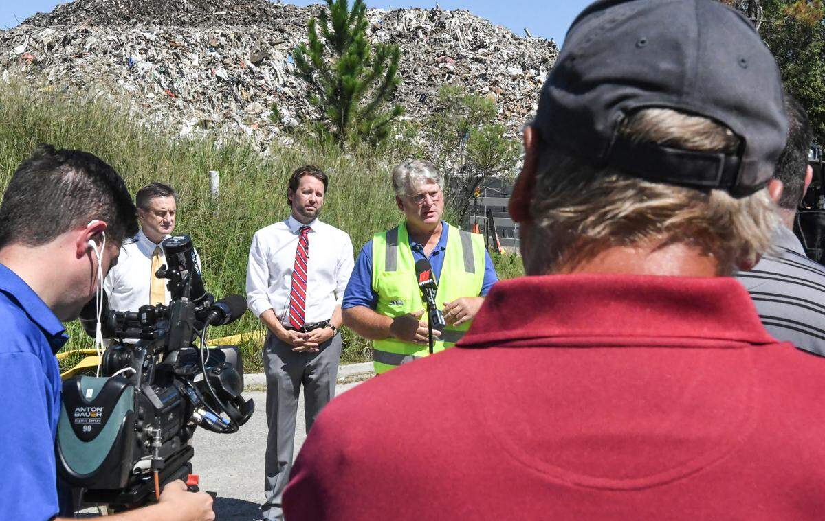 State Sen. Tom Davis, R-Beaufort, back left, and&nbsp;U.S. Rep. Joe Cunningham, D-S.C., back center, listen as Steve Spurlin, U.S. Environmental Protection Agency’s on-scene coordinator and incident commander, addresses the media on Thursday morning in front of the tower of trash at Able Contracting’s Material Recovery Center in Jasper County. Both the EPA and S.C. Department of Health and Environmental Control provided an update on the progress in tearing down the debris pile. Asked about owner Chandler Lloyd’s financial responsibility, Myra Reece, director of environmental affairs with DHEC, said “the responsible party” told the department that he “doesn’t have the financial means to fight the fire.” The EPA’s Spurlin said his agency has spent $500,000 to date and “still have sufficient funds to address fire and runoff control.” Spurlin also assured the elected officials that the air quality is nearing safe levels for the residents, who are staying in nearby hotels, to return. But now they’re concerned that the volume of truck traffic along Schinger Avenue poses a danger. Spurlin told the lawmakers that the EPA has picked up the tab from DHEC on the 10 to 11 families displaced because of the toxic smoke. “We’re spending about $20,000 a week,” he said.&nbsp;