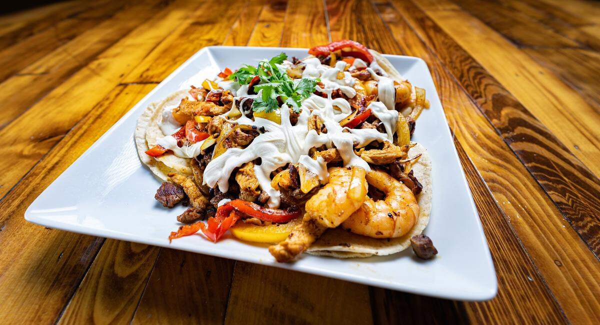 Alambre at Blue Laguna on Hilton Head is steak or chicken and bacon, served with grilled bell peppers and onions, topped with melted Oaxaca cheese over three flour or corn tortillas. Shrimp optional.