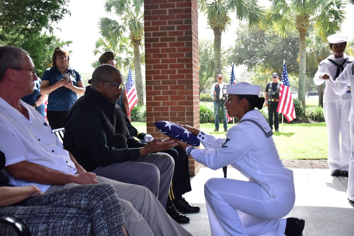 Chaplain Leon Maxwell, accepts a flag from Corpman 3rd Class Selena Munoz during an internment for two Unclaimed Veterans at Beaufort National Cemetery. The two veterans, Donald Brown and David Dickson served in the Navy during the Vietnam War and they were both from the Lowcountry area.