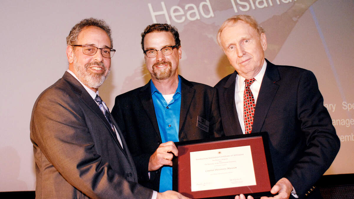 From left, Harold Closter, Director of Smithsonian Affiliations, hands a certificate of affiliation to Coastal Discovery Museum President Rex Garniewicz and board chairman Fred Manske. The announcement that the local museum had been named an affiliate of the Smithsonian Institution was made before the start of a lecture event on Wednesday at Coligny Theatre.