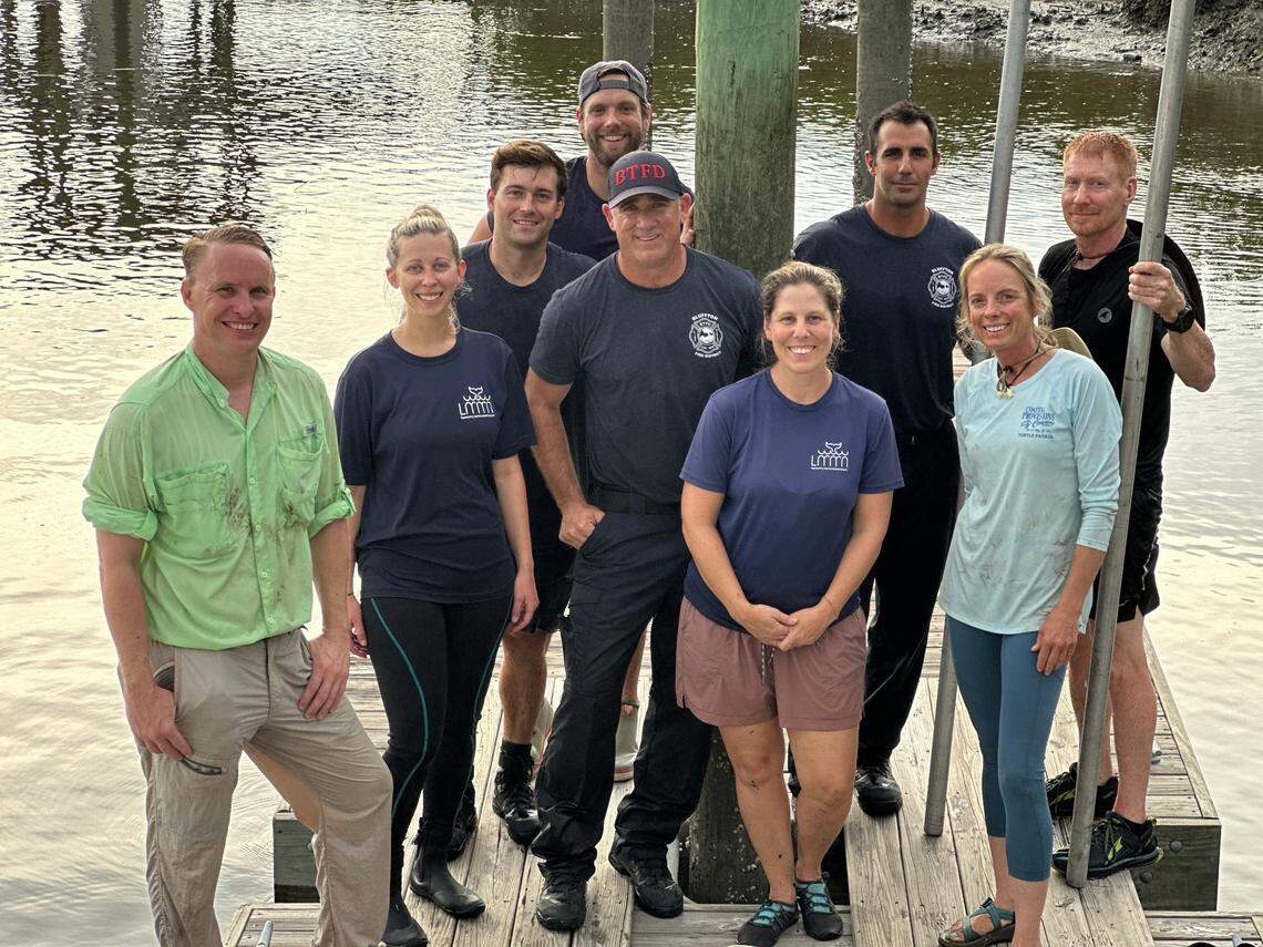 After an approximately 8-foot dolphin was found stranded in a Bluffton-area lagoon the morning of July 12, 2025, a group of rescuers came together to return the mammal to its home in the May River. From left to right: Hampton Lake neighbor and volunteer Michael Smith; Stranding Technician Tracy Kowalczyk of the Lowcountry Marine Mammal Network; Bluffton Township Fire District Senior Firefighter Aaron Angel; LMMN volunteer John Kane (hat turned backwards); BTFD Driver/Operator Tony Crosetto (with BTFD hat); LMMN Executive Director Jane Rust (front center); BTFD Driver/Operator Brandon Driscoll; marine biologist and Sea Turtle Patrol HHI Executive Director Amber Kuehn; and Hampton Lake resident and volunteer Thomas Layer.