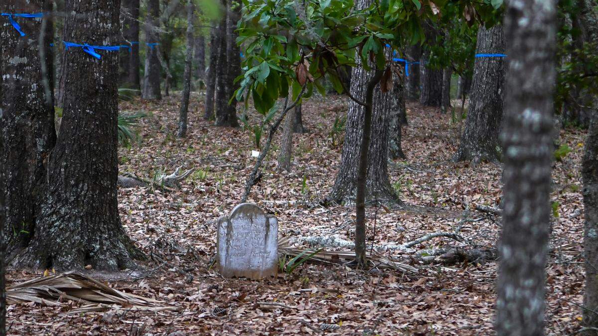 A headstone for Irishman Archibald Strain dated June 16, 1809, sits among surveyed land historically known as Cedar Point Cemetery for a residential home as seen on March 23, 2022 near the gates of Callawassie Island, South Carolina. A July 17 stop work order has halted construction until the land is searched for other graves that might be unmarked.