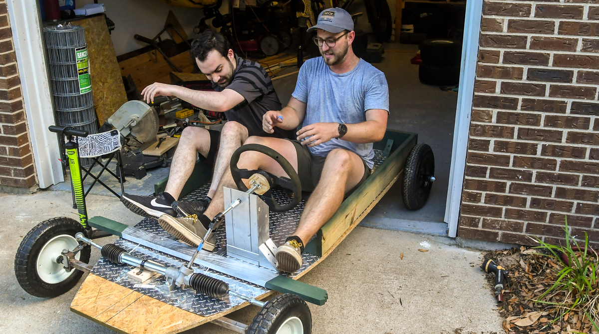 Justin Mankita, left, squeezes into his seat next to Kody Wilson for the first test ride of Gator Bait on Wednesday, June 8, 2022 at Wilson’s Lady’s Island home. Outfitted with a donated golf cart steering wheel, Wilson’s heels are pressed against the car’s breaking system, a spring-loaded piece of lumber that can be pushed against the tires.