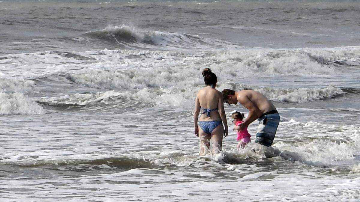 Josh and Cara Denton play with their daughter Addie in the surf on Tuesday morning on Hilton Head Island. The family, visiting from Bristol, Tennessee, made arrangements in June for their condo vacation and decided to make the trip. Whle the beach was practically theirs, they were disappointed that there were very few businesses open. “I completely understand why they did (close),” Josh said. “We’re probably going to pack up and leave on Wednesday..”