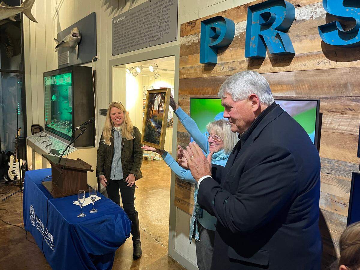 Sharon Stewart holds up a gift she and Dick Stewart, right, received at the Port Royal Sound Foundation Monday when a new research initiative was announced that the Stewarts will help to fund. Executive Director Jody Hayward is at the left.