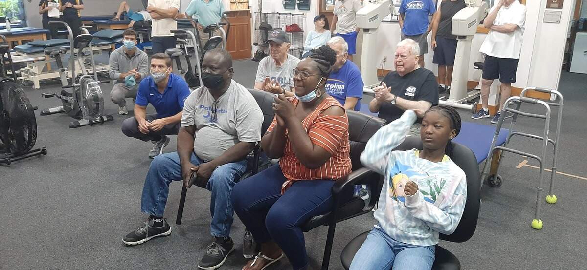 Family and fans gathered Wednesday morning at Carolina Sporstcare and Physical Therapy to watch weightlifter C.J. Cummings of Beaufort compete in the Olympics. From left are Jim Denton of Carolina Sportscare, kneeling, Clarence and Savasah Cummings, C.J.’s parents, and Christin, the daughter of Crystal Cummings, C.J.’s sister.