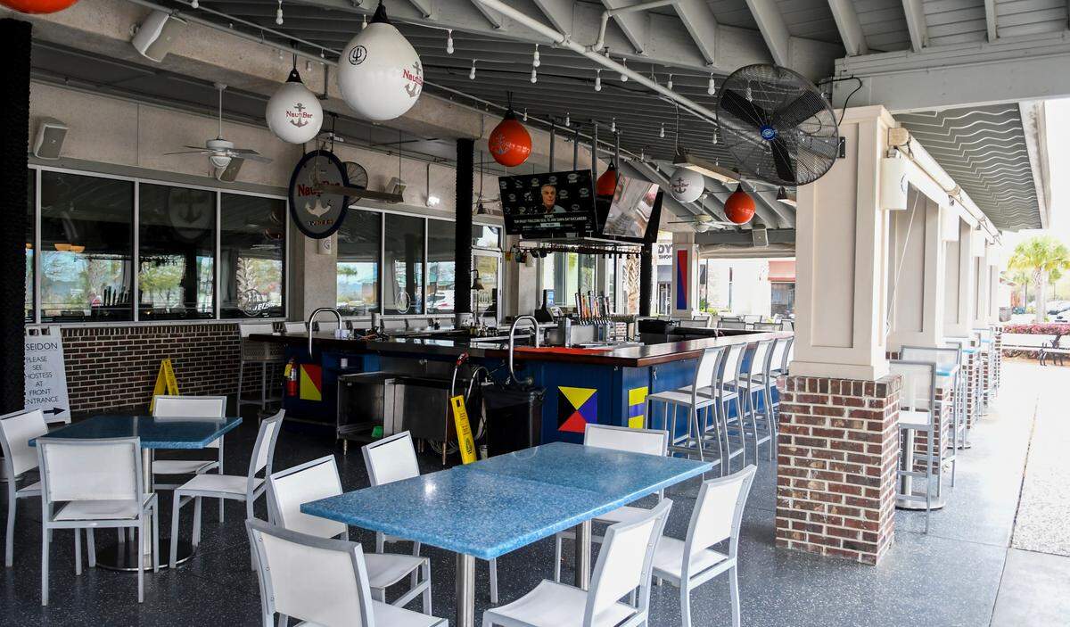 While televisions run and the beer tap handles are still on display, the chairs at the outside bar at Poseidon’s Coastal Cuisine sit empty on Wednesday, March 18, 2020 in Shelter Cove Towne Centre. On Tuesday, S.C. Gov. Henry McMaster closed all seating and dining of restaurants and bars to help combat the spread of the COVID-19 virus.