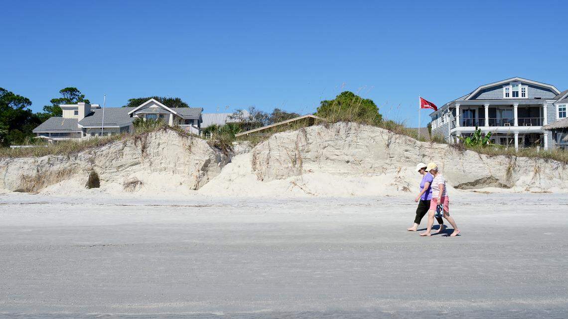 Beachgoers walk past sand dunes eroded by recent high tides along Hilton Head's North Forest Beach on Oct. 14, 2015.