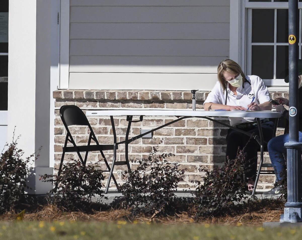 Kimberly Stockstill, NP, sits with a patient, right not seen, at a table on the front porch of Bluffton’s Affordable Healthcare on Thursday, March 12, 2020 who had flu-like symptoms. Jennifer Green, NP, owner of the facility, said they got the idea to see patients outside after seeing hospitals use triage centers in parking lots. If the providers suspect patients need to be tested for the coronavirus, they give patients a mask and send them to the health department. “We don’t have (coronavirus) testing kits,” Green said but stressed that 99% of patients likely have the flu or severe allergies from pollen.
