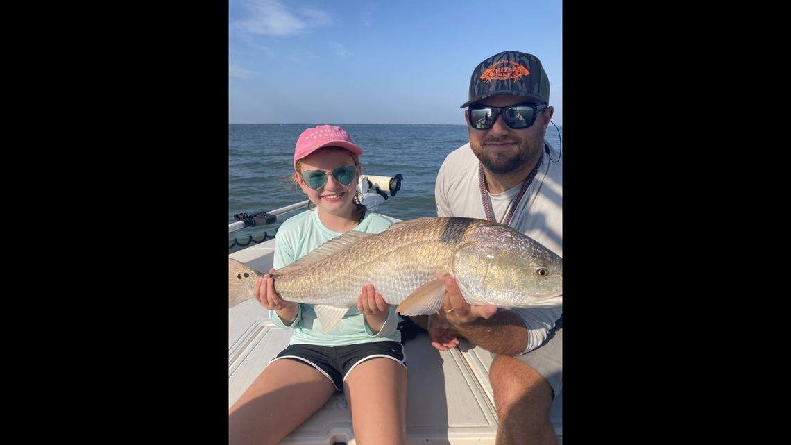 Mike Rentz, a charter boat captain with Salty Sea Charters in Beaufort, and a client display a redfish caught in the Beaufort River.