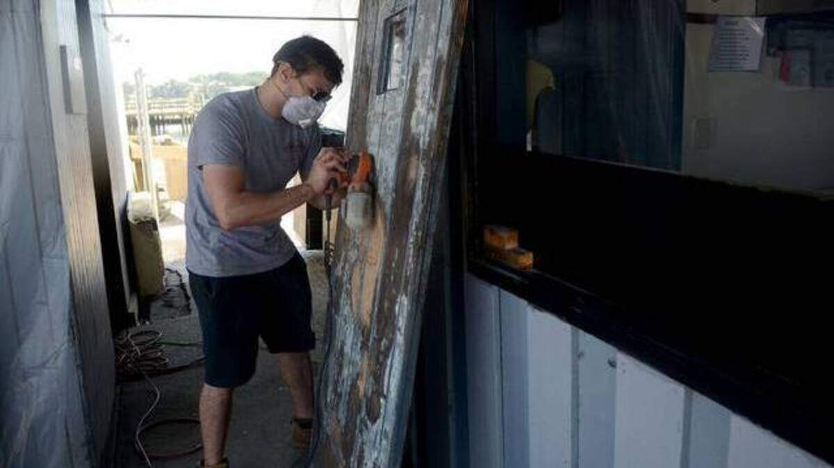 A Hudson’s worker sands a door as volunteers work to clean Hudson’s Seafood House on the Docks after Tropical Storm Irma in 2017.