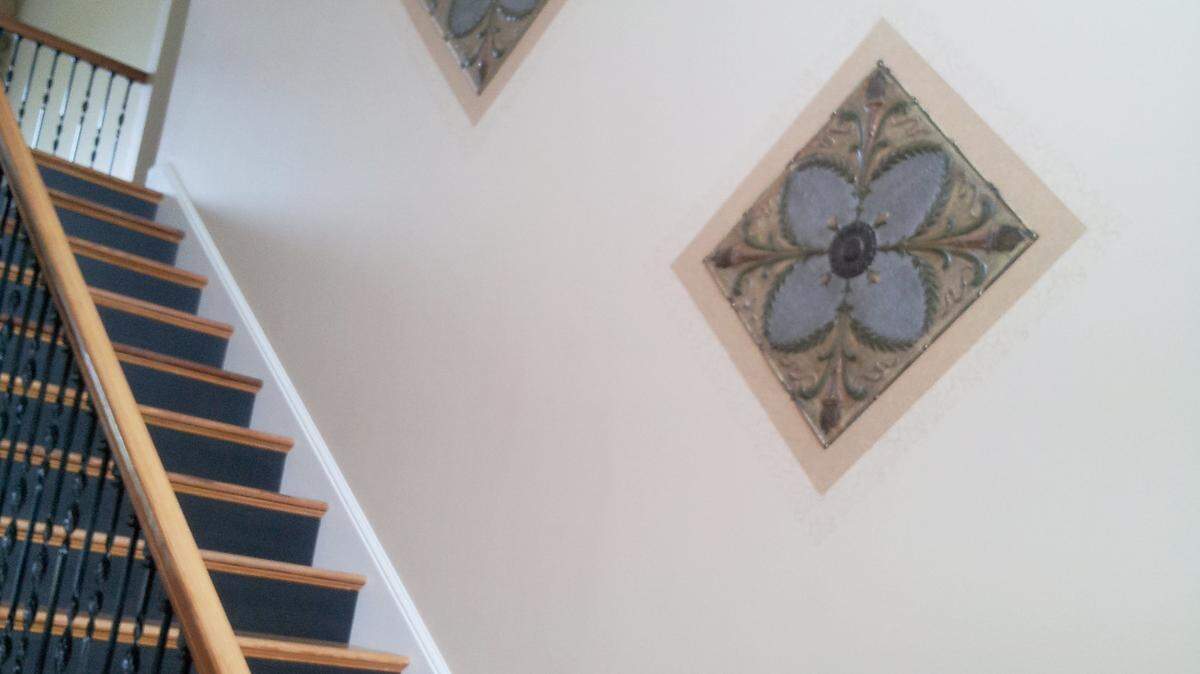 Faced with two large, blank walls in her foyer, Sue Cheatham of St. Helena Island used the space to showcase her love for old architectural pieces. On the stairway wall, Cheatham mounted old tin ceiling tiles and stenciled frames around them.