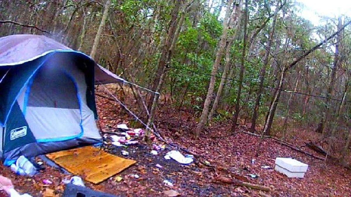 Dwellings of a homeless person who is living by a retention pond with an alligator in it.