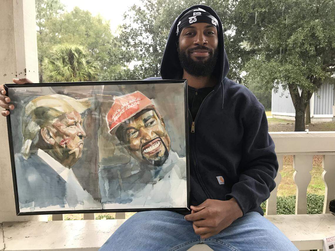 Ment Nelson poses with his painting, “Kissin’ Up,” which depicts President Donald Trump and rapper Kanye West after their meeting in the White House in October. Nelson recently listed the painting for $1 million.