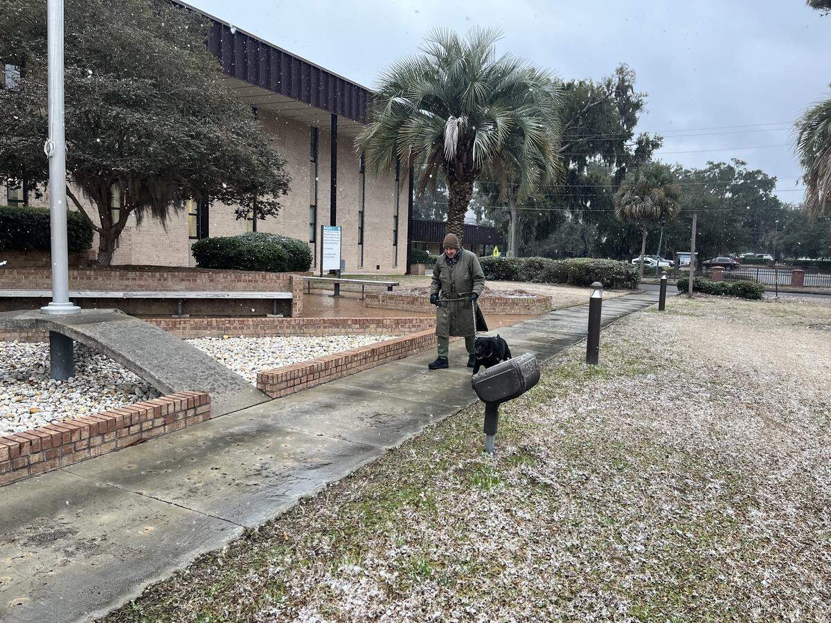 A man walks his dog at the Technical College of the Lowcountry in Beaufort Saturday afternoon as snow began to fall.