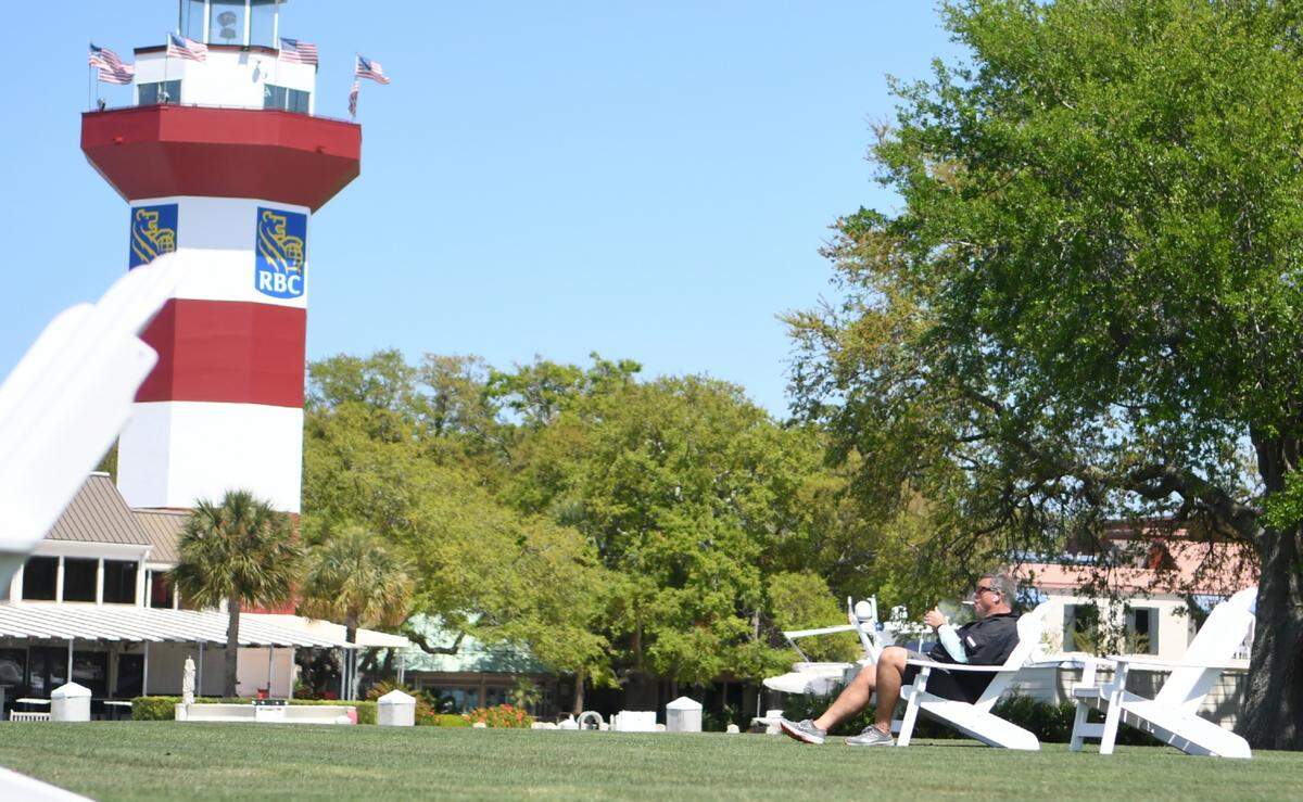 Sitting in an Adirondack chair near the 18th green of Harbour Town Golf Links with the iconic Harbour Town Lighthouse in the background, Kim Gary listens to an audio book on Thursday, April 2, 2020, enjoying a cigar and gazing into Calibogue Sound. A recent homebuyer, Gary hasn’t been thrilled in how the locals wanted to close down the bridge: ”I hope this (pandemic) gets people to treat others with respect. If everyone does their part, we’ll be okay.”