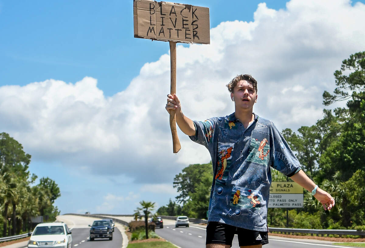 In the sweltering sun, Nolan Felts, 18, stands in the narrow median of Palmetto Bay Road on Tuesday, June 9, 2020, holding a handmade Black Lives Matter sign as the Cross Island Parkway rises behind him on Hilton Head Island. Felts, visiting the island from Nashville, Tennessee, said it was important for him to protest instead of vacationing — saying his parents are very supportive. “This is a very serious issue,“ Felts said as several drivers passed, honking in support. “This is my third day and I’m going to be out here everyday until we leave.”