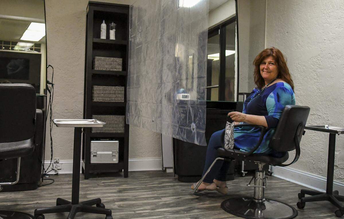 While holding her face mask, Michelle Casey, owner of Chez Michelle Salon, sits for a portrait on Friday, May 15, 2020 on Hilton Head Island. Casey is taking Monday’s opening of salons and other close contact businesses seriously, and among other things, has installed a shower curtain to act as a simple divider between styling chairs. Casey said she’ll “reevaluate after 30 days but the salon itself is not taking new clients at the time to keep everybody safe.”
