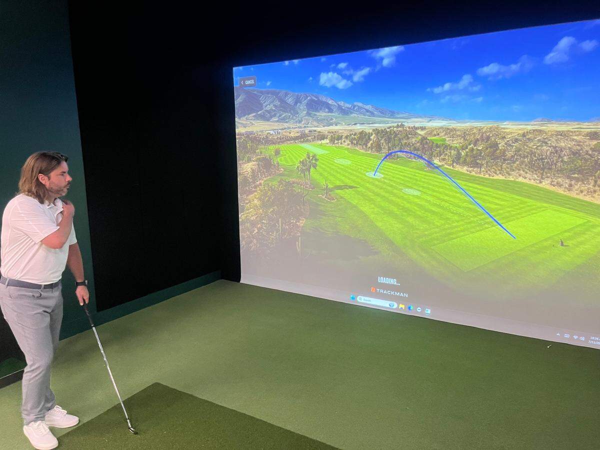 Chad Troutman checks out the path of his swing after hitting a shot at one of four simulator bays at Egret and Iron in Beaufort, which he is opening Friday with partner Andrea Michel.
