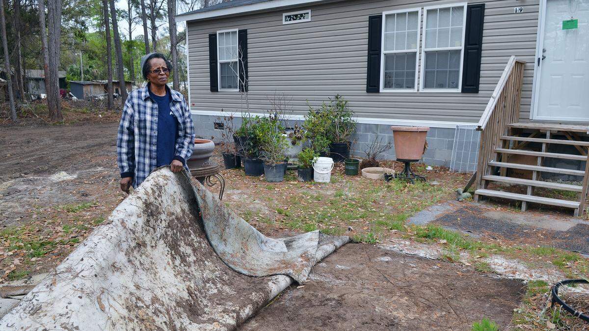 Rhiner Drive resident Doris Grant recently was able to shut down her septic system when Hilton Head No. 1 PSD's installed sewer lines on her street. Here, she is photographed on March 26 pulling back the cover she had placed over her old septic tank in front of her  home.