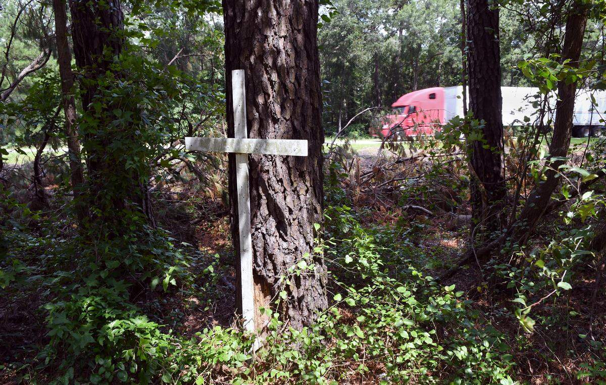 A southbound semi rolls past a cross placed next to a large tree that was the site of a long-ago accident in the median of I-95 near mile marker 11 in Jasper County. Many lives have been claimed over the years by motorists striking trees along this stretch of road that that has been nicknamed the “coffin corridor.” At the time this photo was taken on July 27, workers were just beginning to cut down the trees from this portion of the highway’s median. The trees in this photo -- and the cross -- have since been removed.