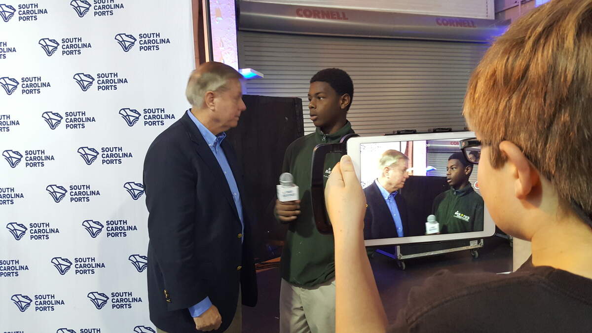 “Backpack Journalists” Amir Wells, center, and Tyler Bowen interview U.S. Sen. Lindsey Graham at a major announcement by the S.C. Ports Authority. They have been in the program for five years.