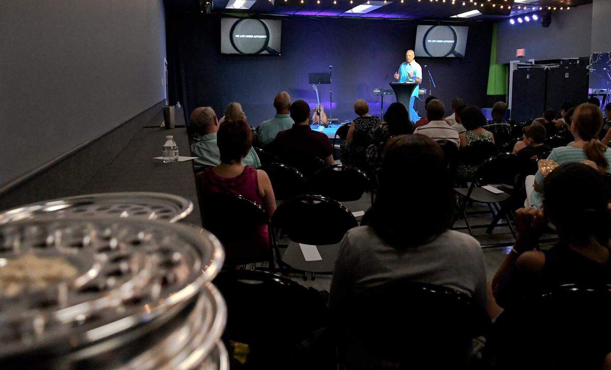 Pastor Michael Beaumont, with Live Oak Christian Church, preaches before his congregation on Sunday, August 5, 2018 at Bluffton Dance Studios in Bluffton as he discusses the Scripture of Titus. In the foreground rests communion trays which rests on make-shift tables that cover the ballerina bars along the wall. The church pays rent at the dance facility and have vowed to leave much of the infrastructure they installed when they begin building their own facility which not only will they hold church but expect to use as a performing arts center. Five volunteers with the church hang up signage, unpack chairs, cover mirrors and windows, storing their equipment in a shipping-type container on the dance school grounds.