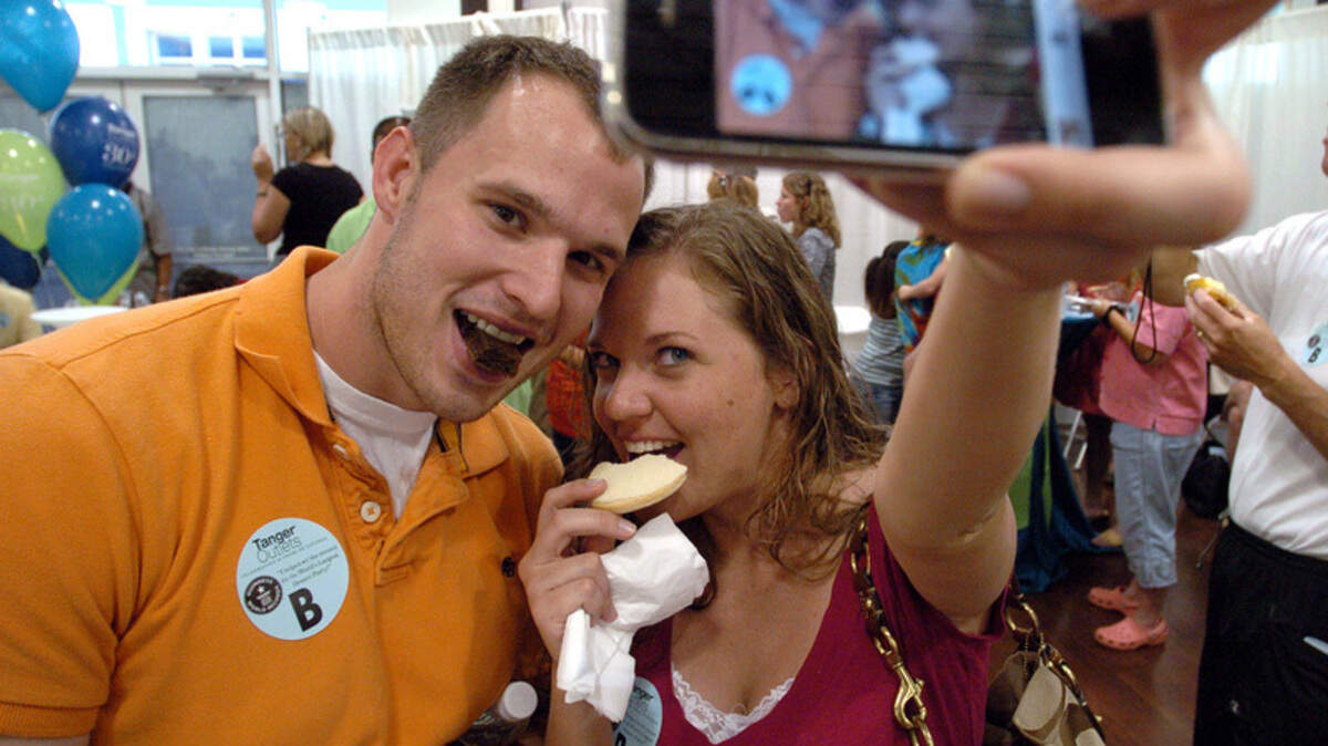 Kyle Gardner and Alissa St. John photograph themselves Thursday as they enjoy dessert at Tanger Outlet Center 2 in greater Bluffton. The outlet chain, celebrating its 30th anniversary, arranged the event in an attempt to set a world record for the "Largest Dessert Party," a new category created by the Guinness Book of World Records. Similar events took place at Tanger's headquarters in Greensboro, N.C., at each of its 34 outlet centers in 22 states and on the floor of the New York Stock Exchange. Auditors from Guinness were to count all the participants to determine whether Tanger set a new record.