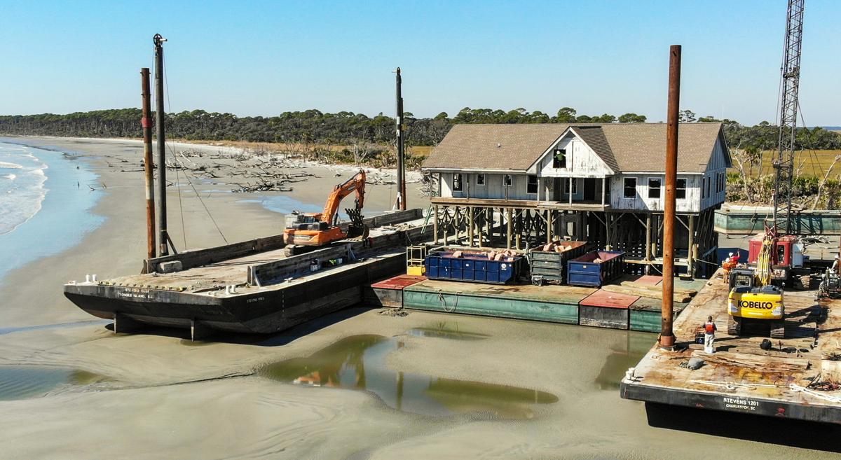 A worker looks out of an access cut into the gabled roof of USCB’s former maritime laboratory as work begins to remove the structure on Monday, Oct. 24, 2022 on Pritchards Island.