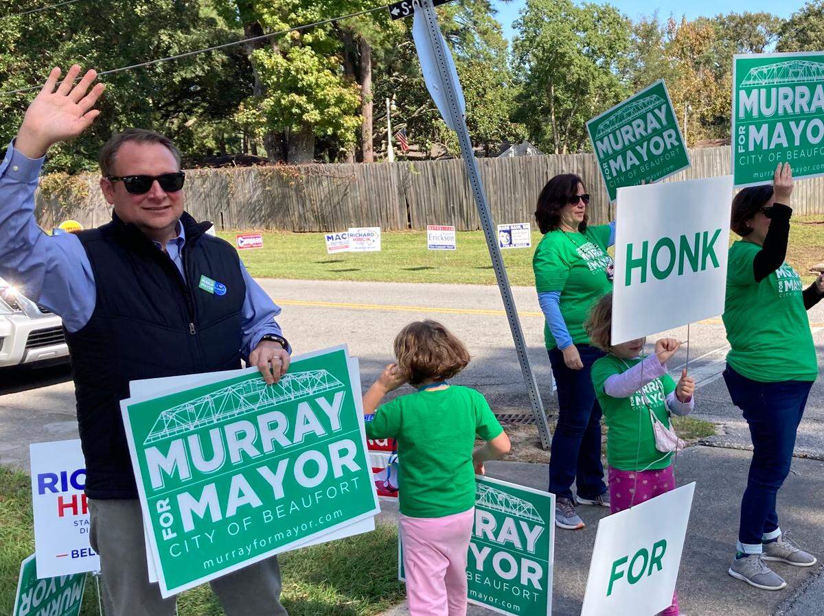 Stephen Murray, left, waves to passing cars on Mossy Oaks Road in Beaufort while campaigning for mayor with his family on Tuesday afternoon.