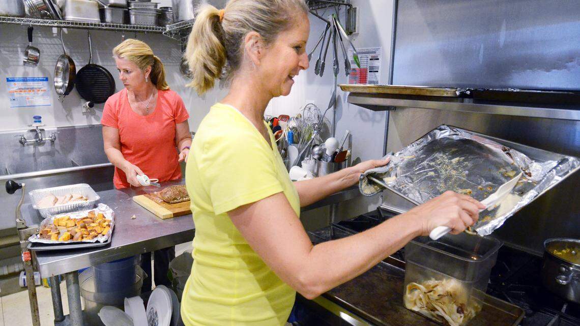 Sisters Leigh Ann Pingree, left, and Michelle Clark prepare roasted pork loin at The Kitchen on Thursday. The Kitchen is a catering and meal-made-to-order business that just opened on Lady's Island.