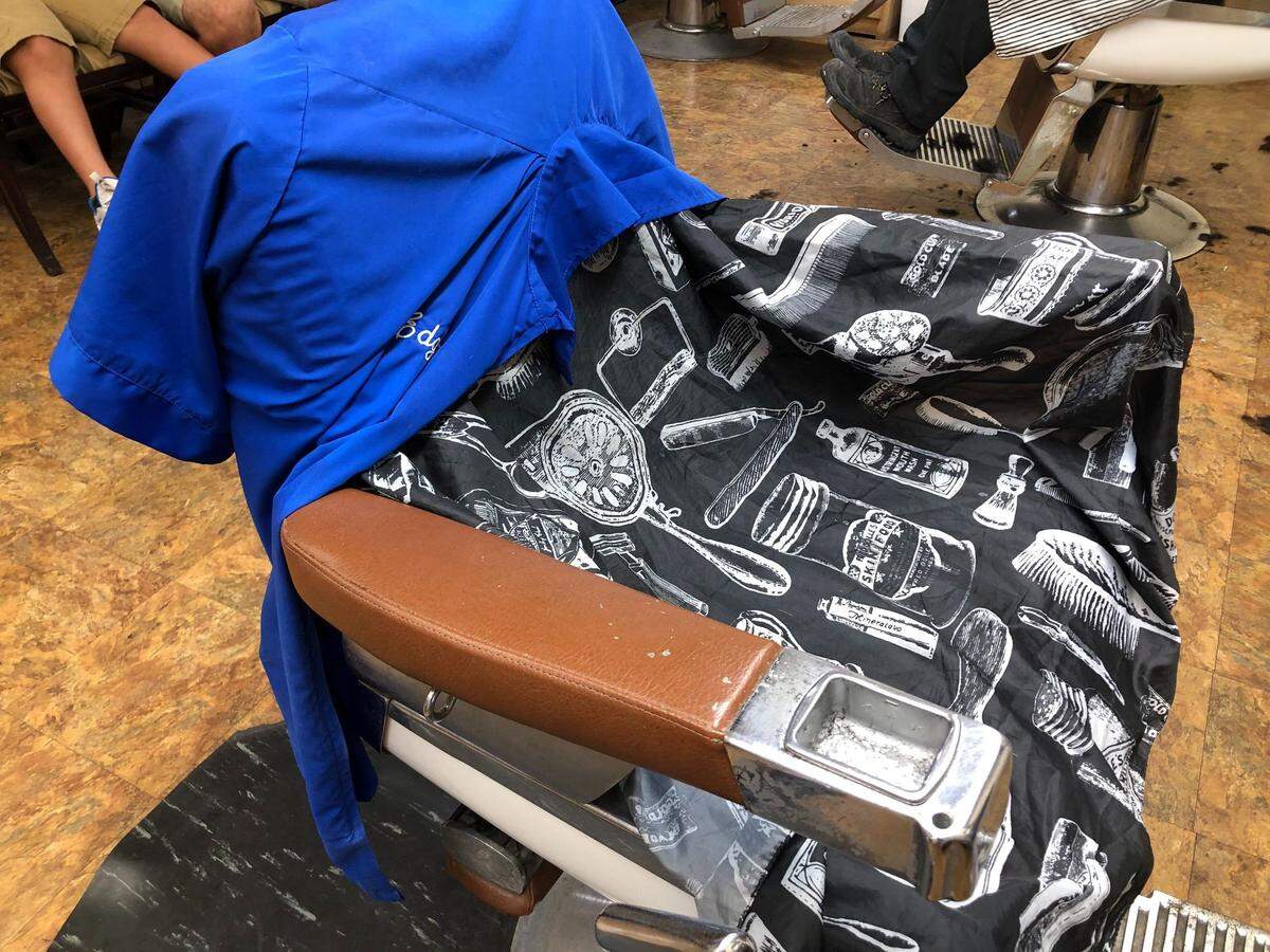 Edgar Cuenca’s barbershop jacket rests right where he left it last Saturday, on a chair now facing a makeshift memorial to the shop owner.